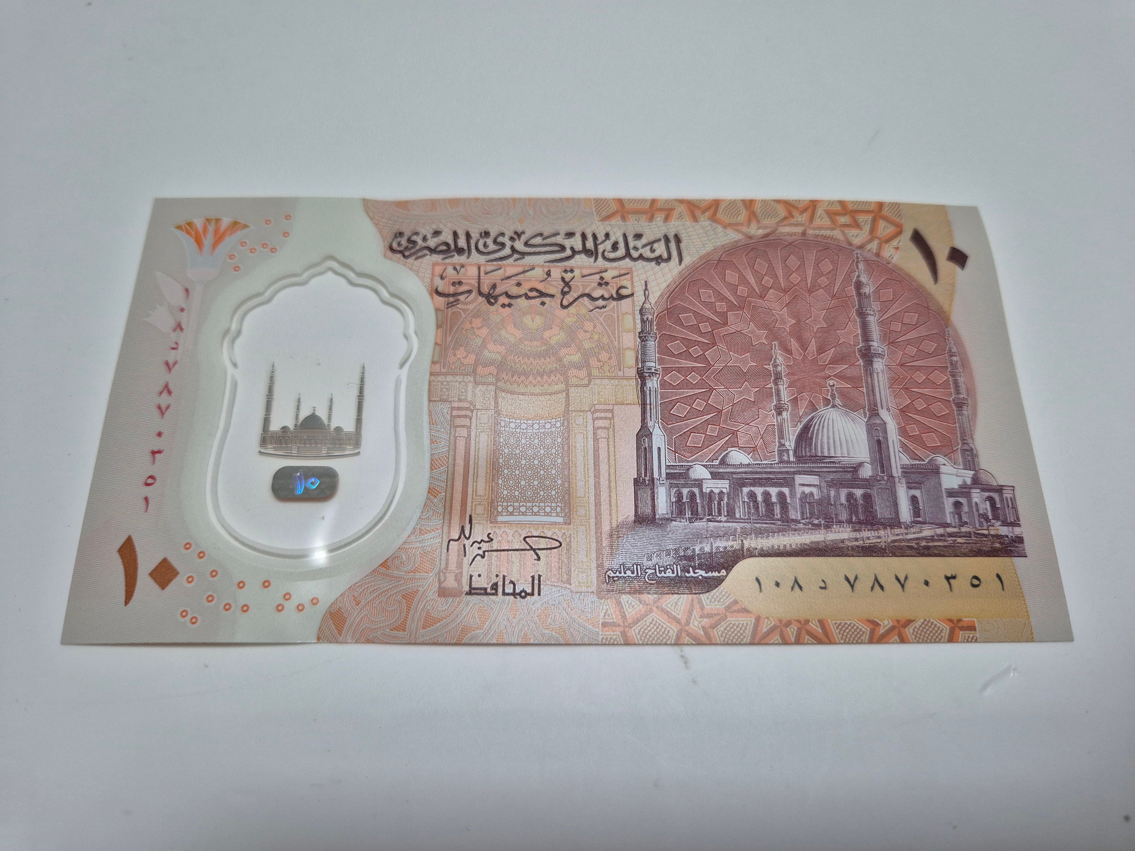 Genuine Egyptian 10 Pound banknote featuring historical designs, displayed flat with detailed imagery and security features.